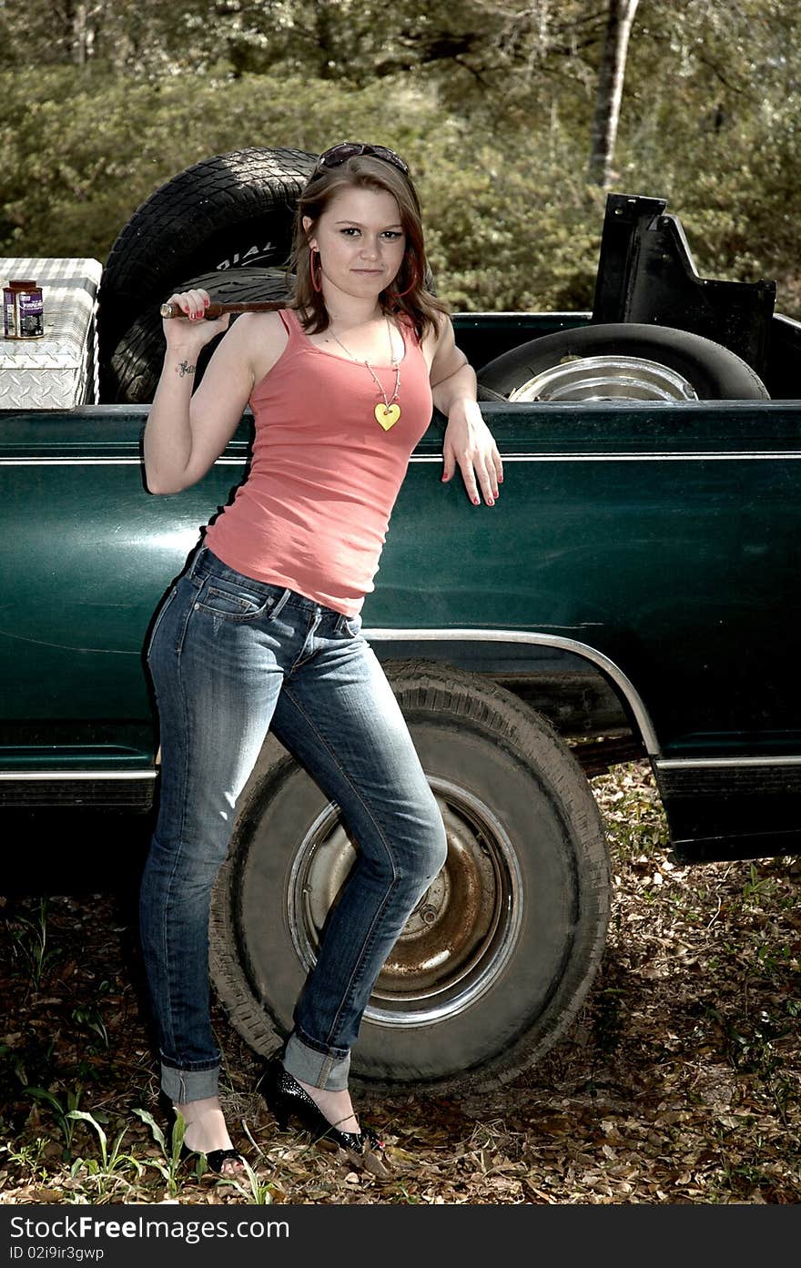 Young pretty woman in high heels standing next to a truck with tires in the back and a tool box holding a tire tool. Young pretty woman in high heels standing next to a truck with tires in the back and a tool box holding a tire tool