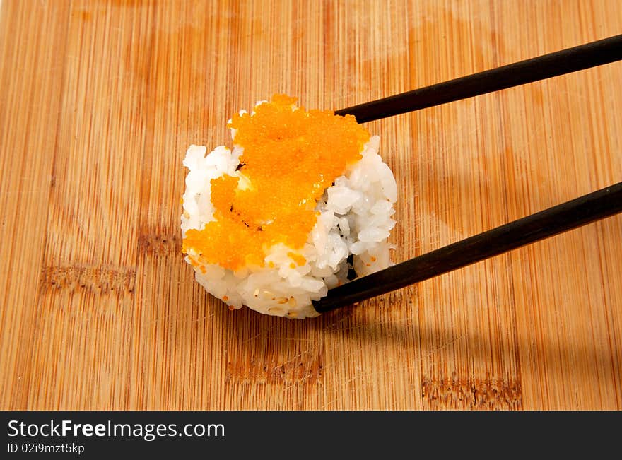 Piece of chopped scallop roll being picked up with a pair of chop sticks. Close up. Piece of chopped scallop roll being picked up with a pair of chop sticks. Close up