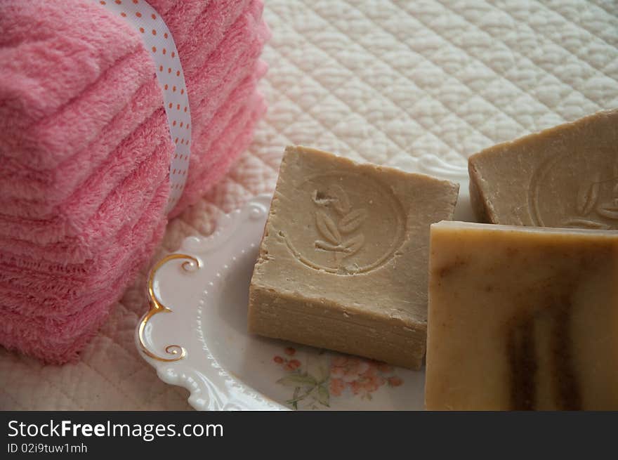 Rustic soaps in a pretty floral porcelain dish, with a stack of pink washcloths. Rustic soaps in a pretty floral porcelain dish, with a stack of pink washcloths.