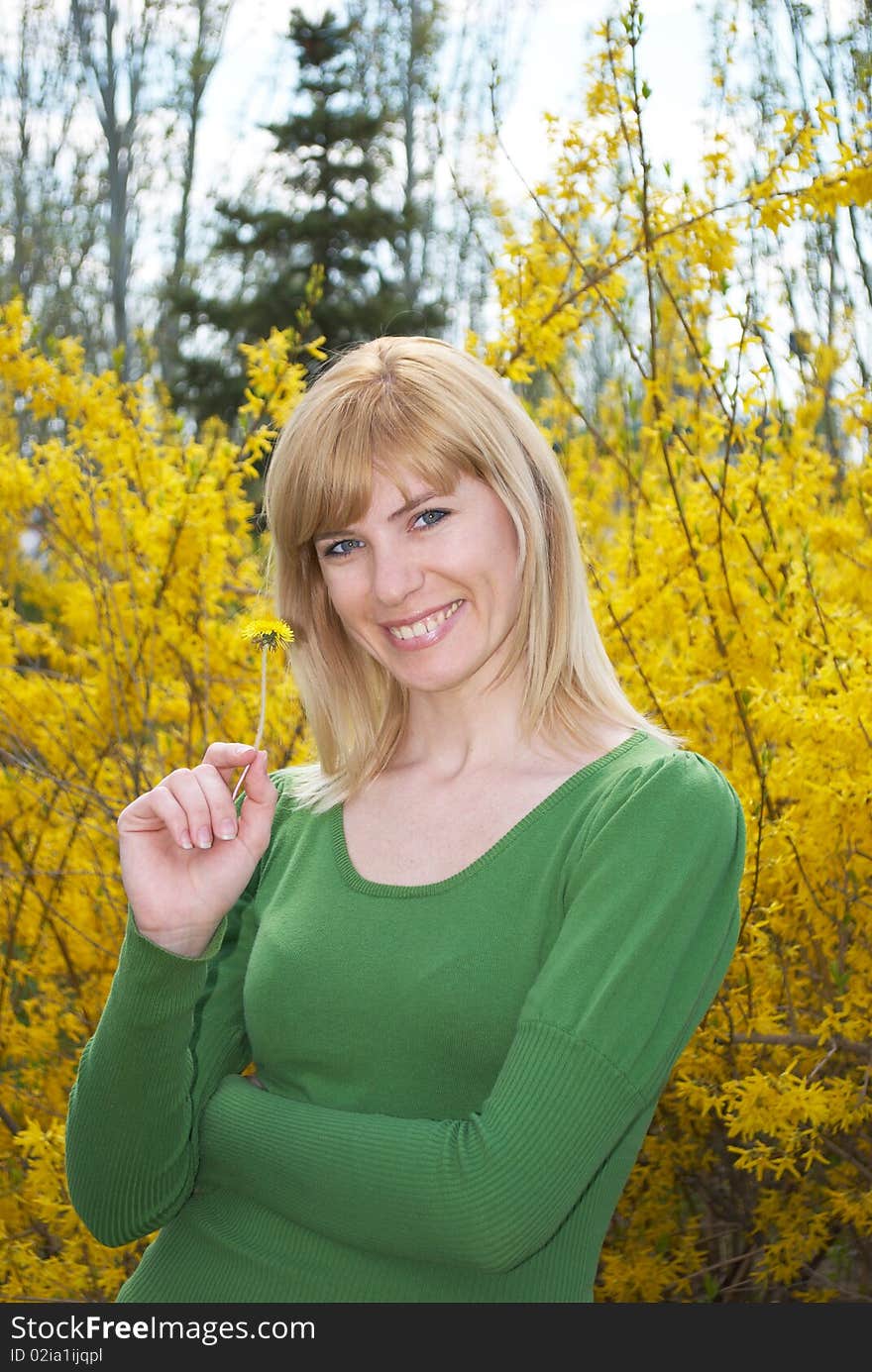 The young woman among yellow flowers in the spring