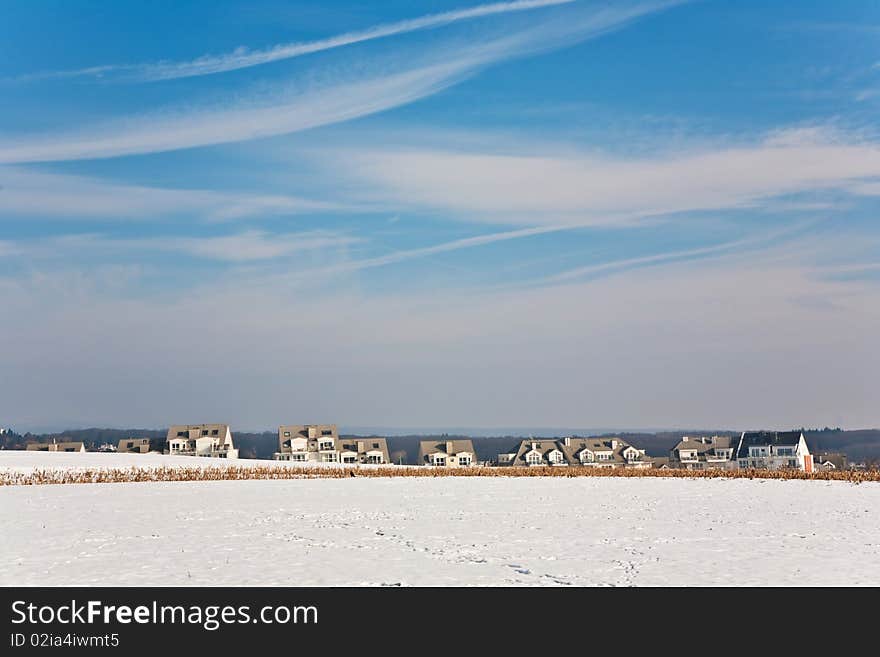 Landscape with  housing area in snow and blue sky