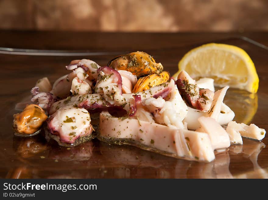 Photo of seafood salad with lemon slice on glass plate