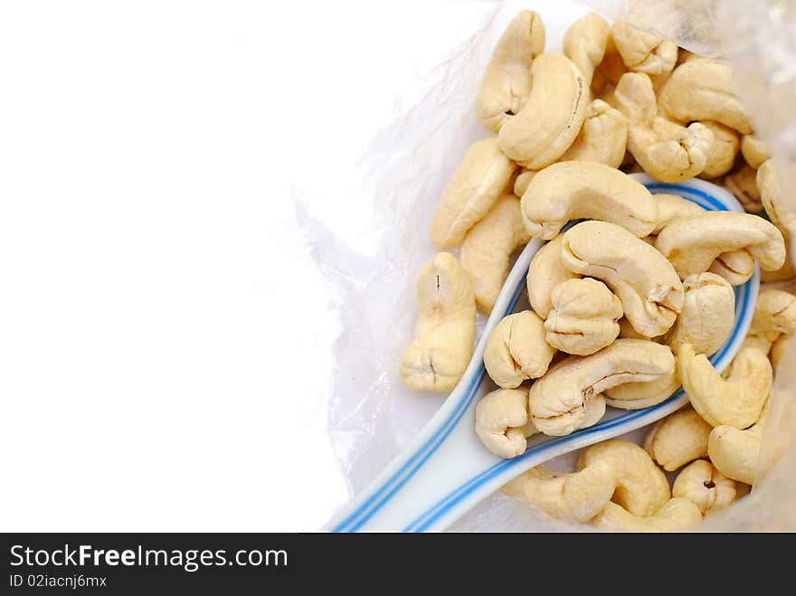 Spoonful of cashew nuts isolated on white with some textured background. Signifying food and beverage, and healthy and nutritious eating. Spoonful of cashew nuts isolated on white with some textured background. Signifying food and beverage, and healthy and nutritious eating.