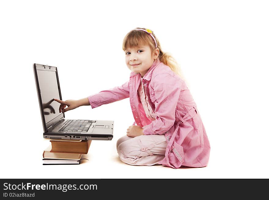 A little girl sitting at a laptop on a white background. A little girl sitting at a laptop on a white background