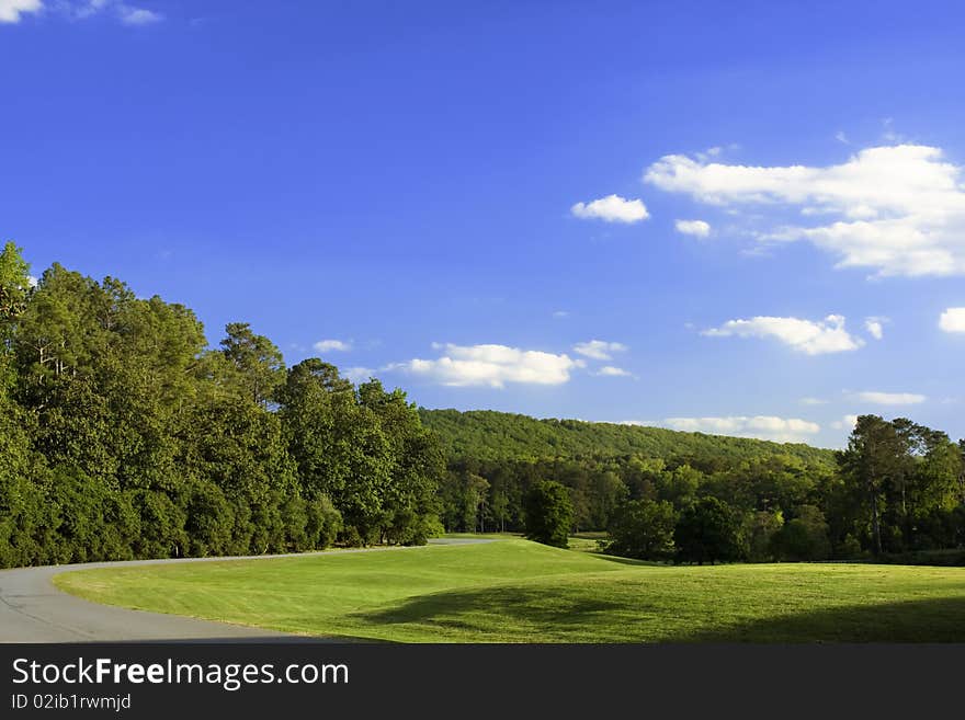 Blue sky, curved road, green grass and trees. Blue sky, curved road, green grass and trees