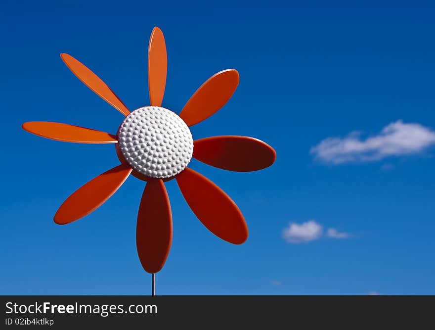 A vintage plastic flower windmill on a blue sky.