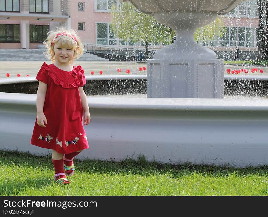 Blond girl on the walk near the fountain