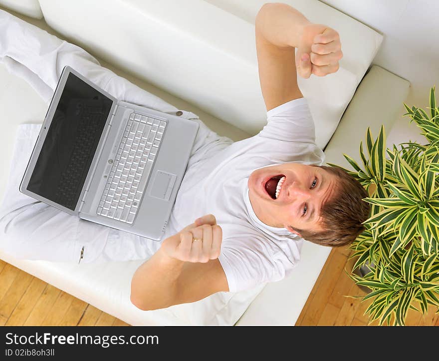 Top view of a happy youngman sitting on couch and using laptop. Top view of a happy youngman sitting on couch and using laptop