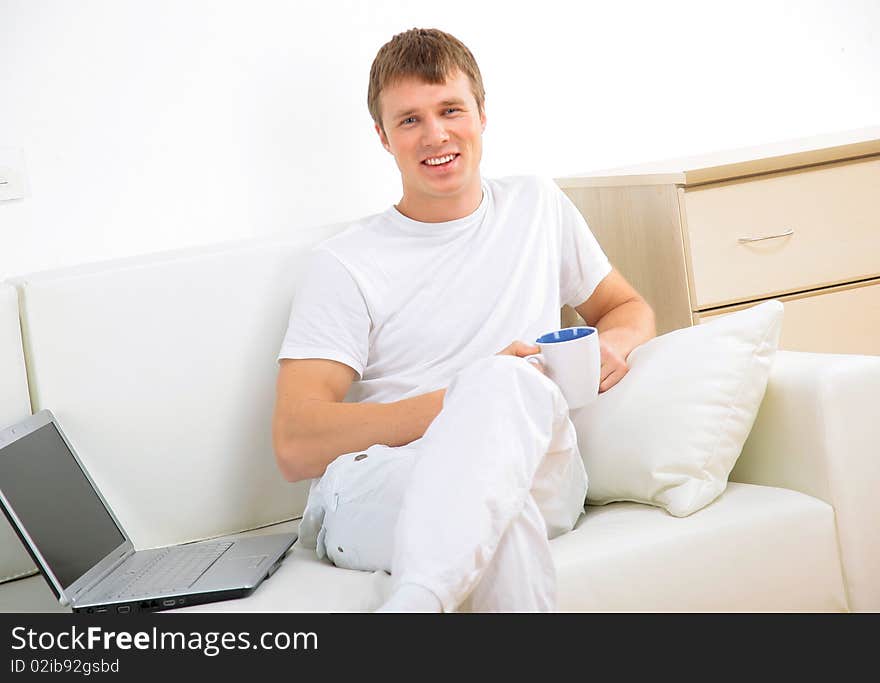 Smiling young man working on laptop computer at home