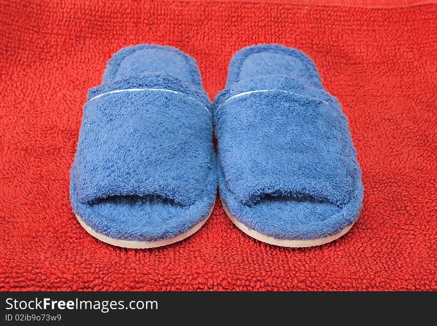 Blue terrycloth slippers on a red background. Blue terrycloth slippers on a red background.