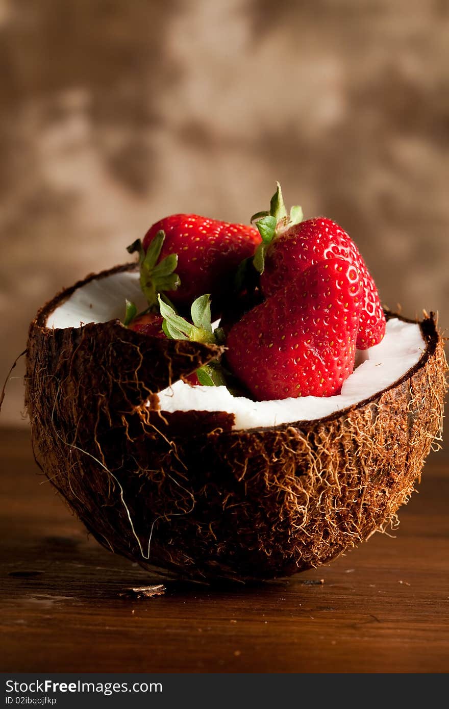 Pohto of a broken coconut with red fresh strawberries inside. Pohto of a broken coconut with red fresh strawberries inside