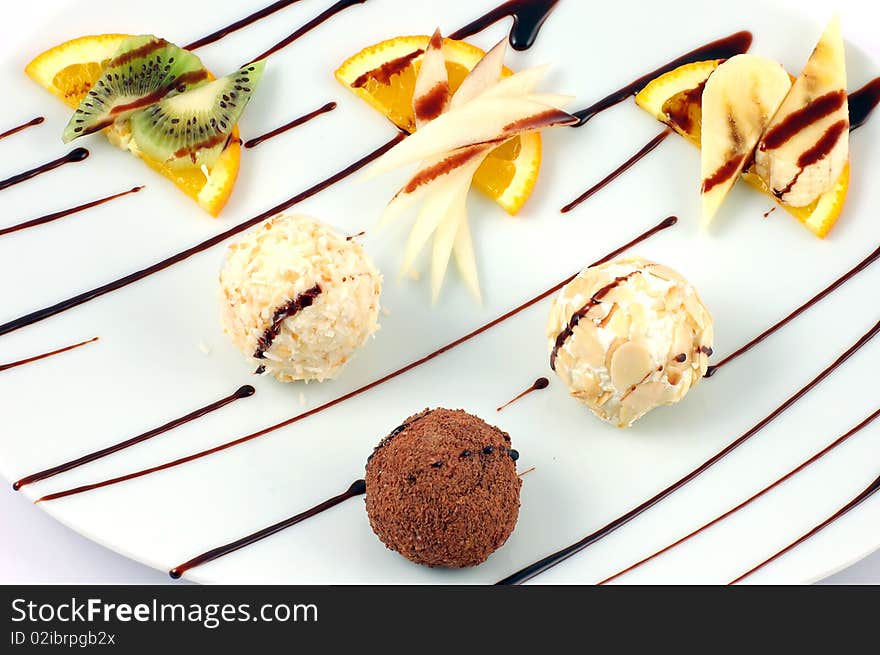 Fresh dessert from fruit and chocolate spheres on a white dish