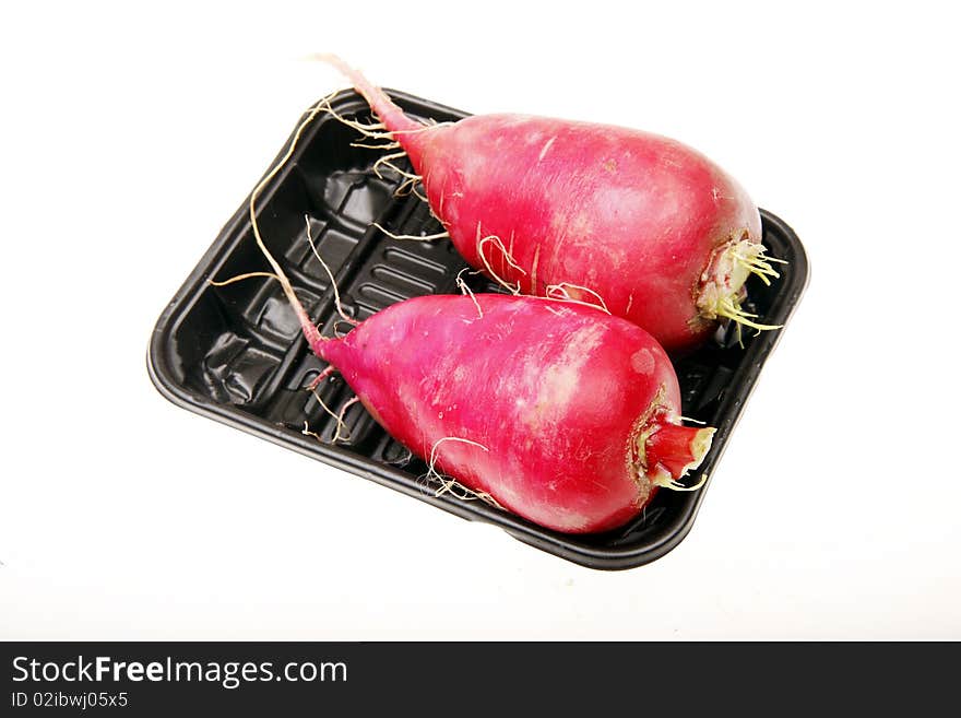 Two fresh red radish in a dark plastic box.(on white)