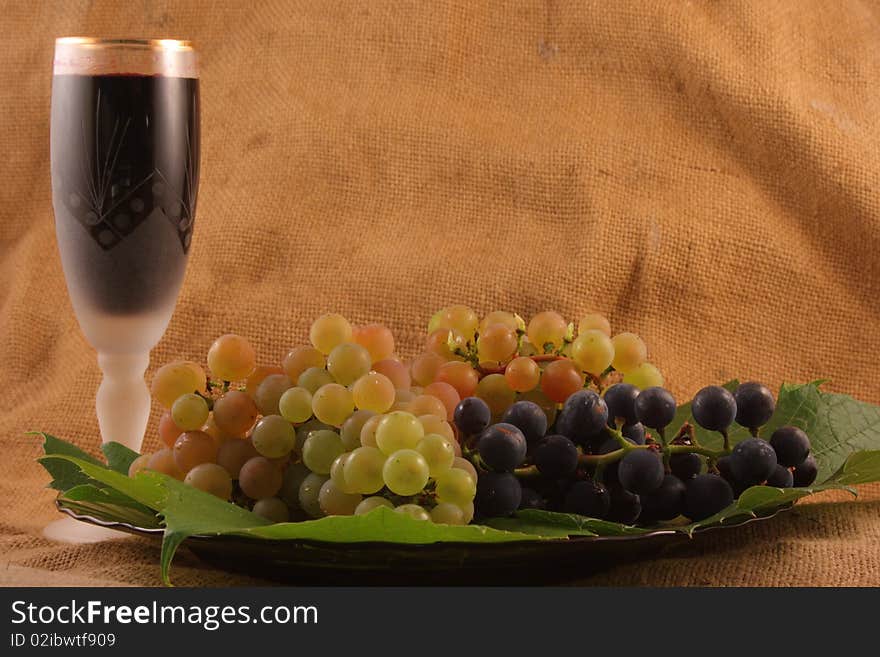 Glass of wine, grapes on a plate on the old background