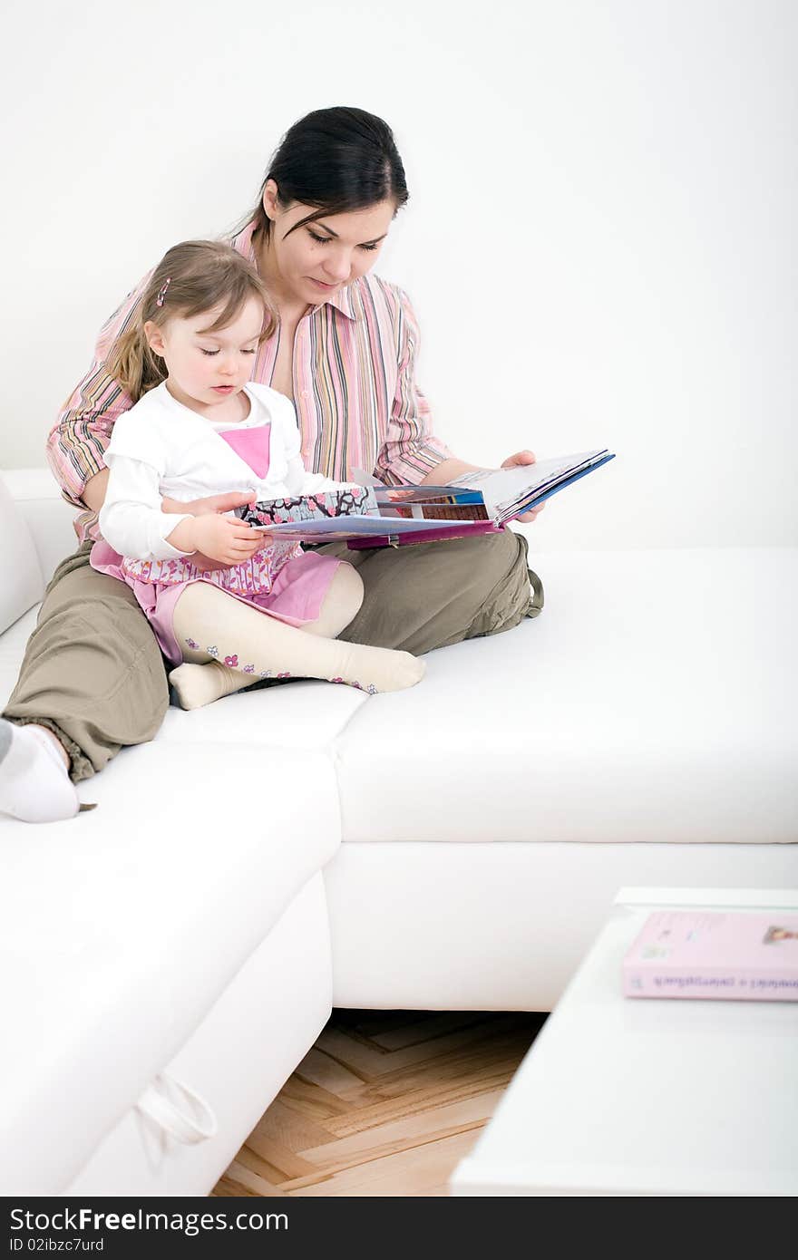 Mother and daughter reading book at sofa