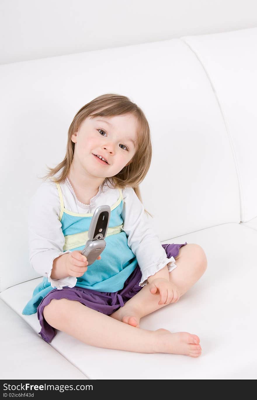 Little girl with mobile phone on sofa