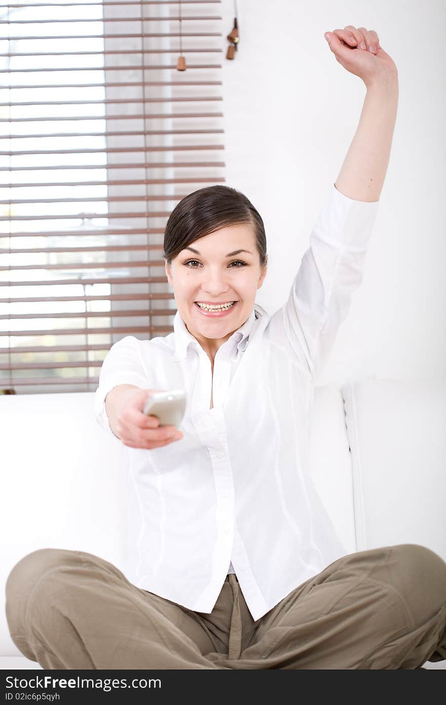 Young happy woman sitting on sofa with remote control. Young happy woman sitting on sofa with remote control