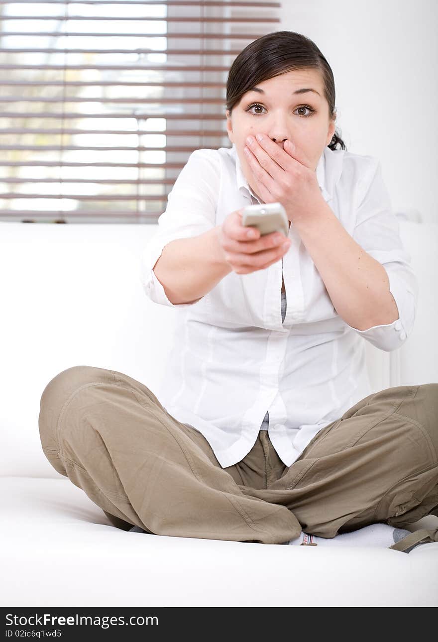 Young happy woman sitting on sofa with remote control. Young happy woman sitting on sofa with remote control