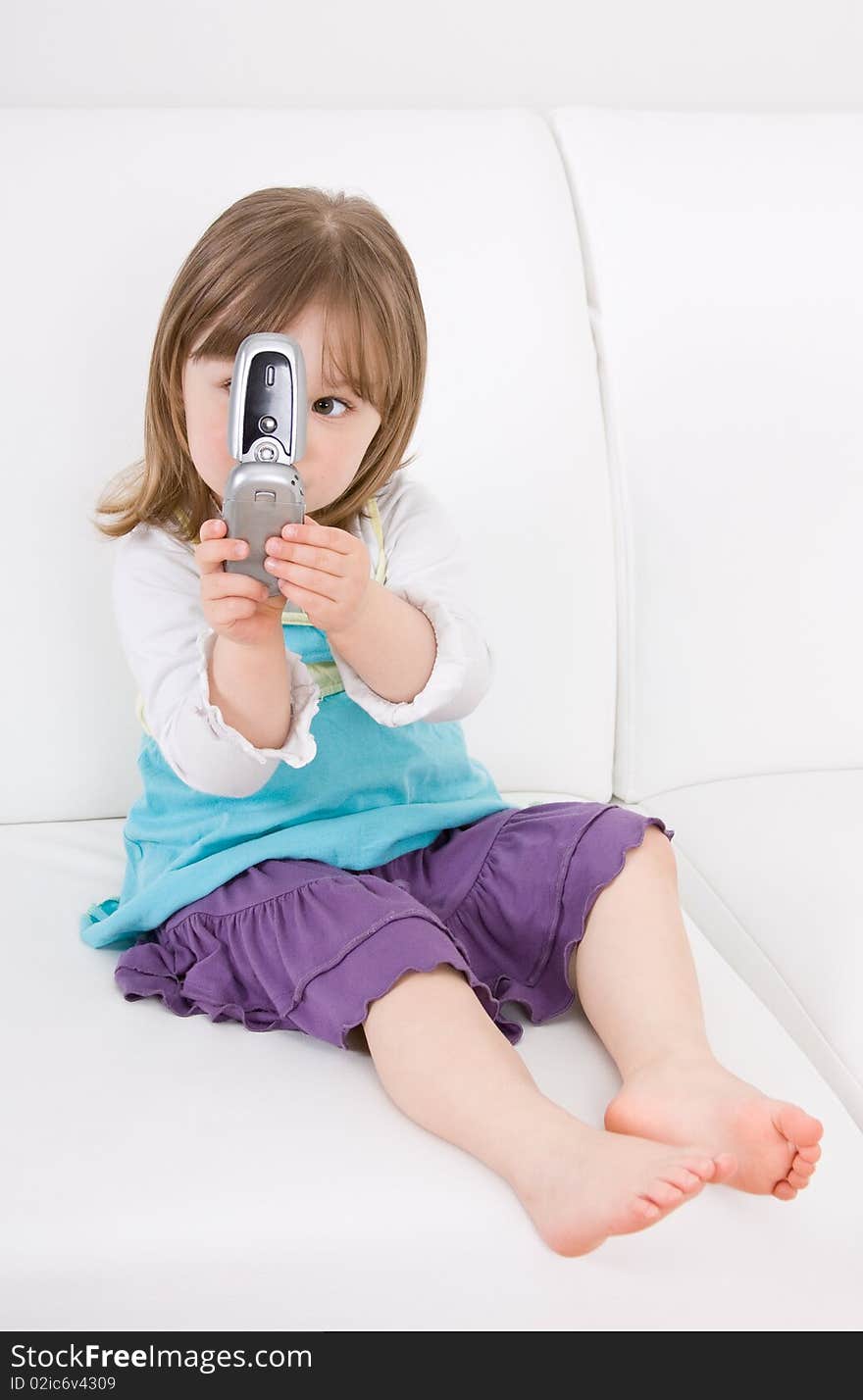 Little girl with mobile phone on sofa