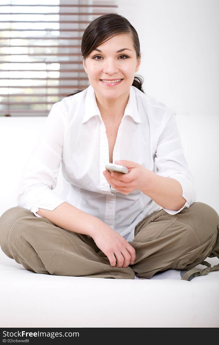 Young happy woman sitting on sofa with remote control. Young happy woman sitting on sofa with remote control