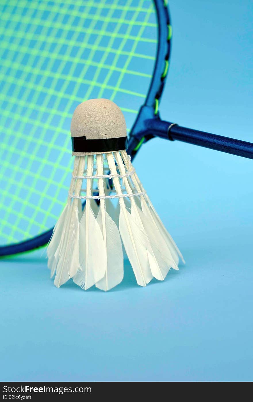 The main focus of the picture is the shuttercock and the racket just as additional subject with a blue background. The main focus of the picture is the shuttercock and the racket just as additional subject with a blue background