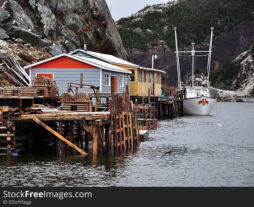 Fishing wharf or pier with buildings and a boat docked alongside at the end of a fjord. Fishing wharf or pier with buildings and a boat docked alongside at the end of a fjord.