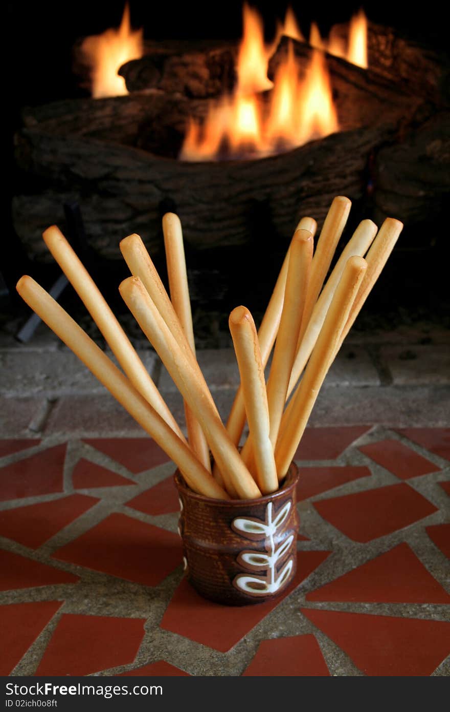 Bread sticks in a dish with a fire in the background.  Low light image. Bread sticks in a dish with a fire in the background.  Low light image.