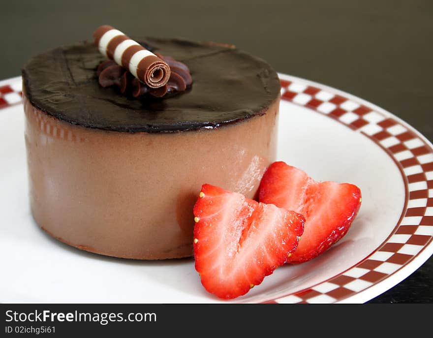 Chocolate dessert with fresh strawberries on a white plate with a dark background. Chocolate dessert with fresh strawberries on a white plate with a dark background.