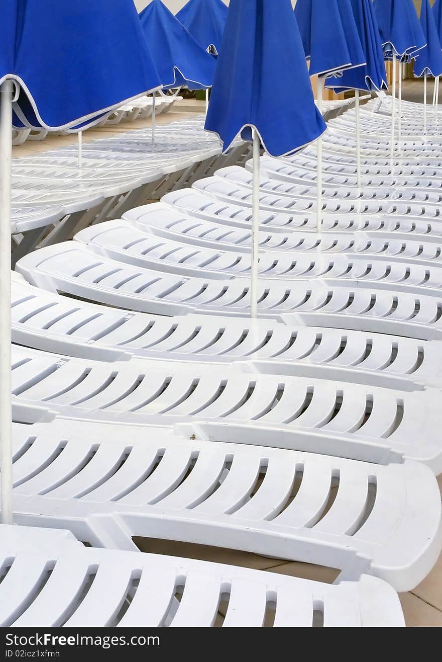 Chaise-longues and parasols standing in several lines