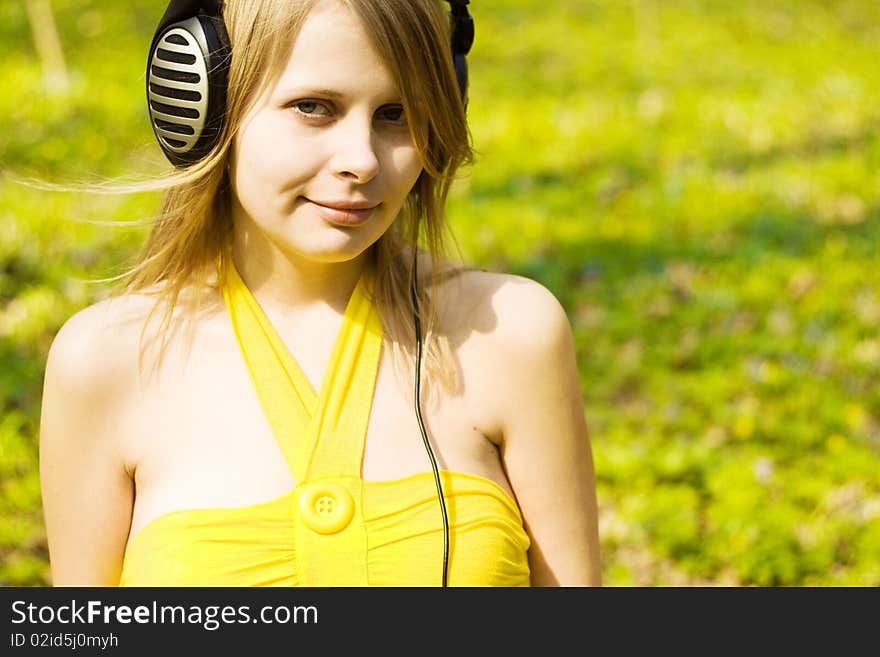 Blond girl listening music in headphones outdoors