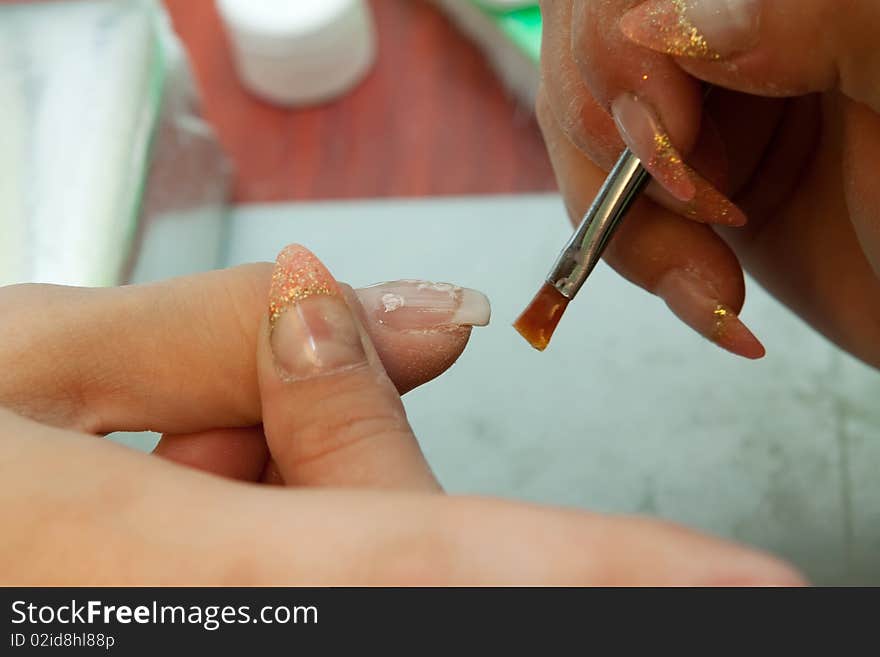 Manicurist applying clear polish on customer. Manicurist applying clear polish on customer