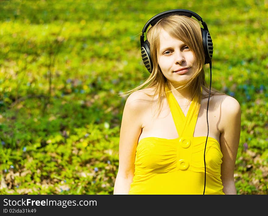 Blond girl listening music in headphones outdoors