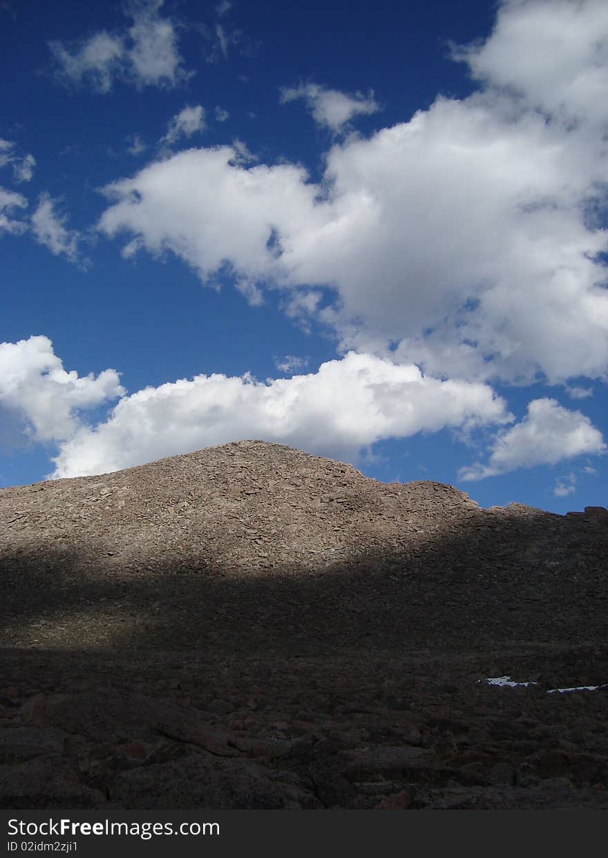 A mountain of boulders peeks though the shadows of overhead clouds. A mountain of boulders peeks though the shadows of overhead clouds.