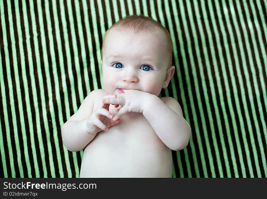 Baby laying on a striped blanket sucking on his fingers. Baby laying on a striped blanket sucking on his fingers.