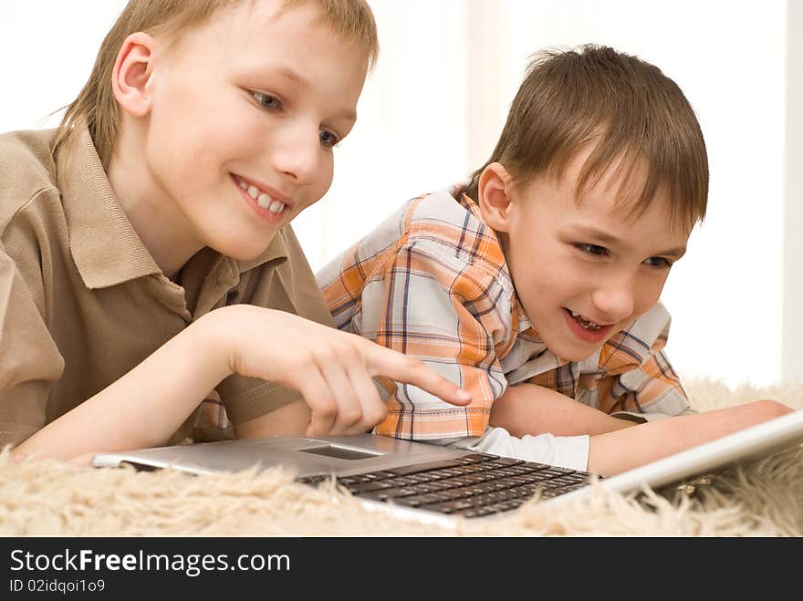 Brothers lie on the carpet with laptop. Brothers lie on the carpet with laptop