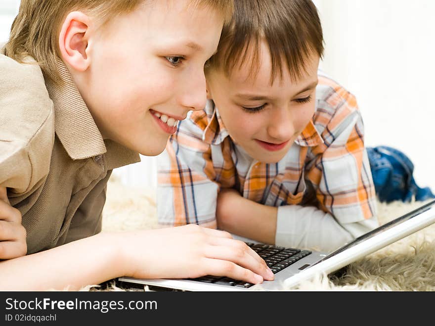 Brothers lie on the carpet with laptop. Brothers lie on the carpet with laptop