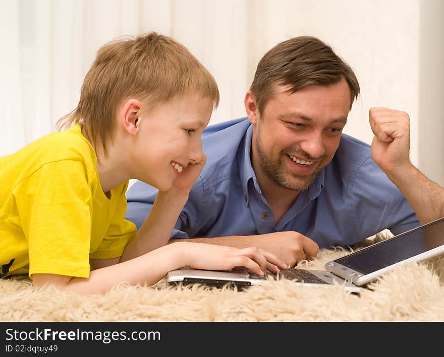 Father and son is on the carpet with laptop. Father and son is on the carpet with laptop