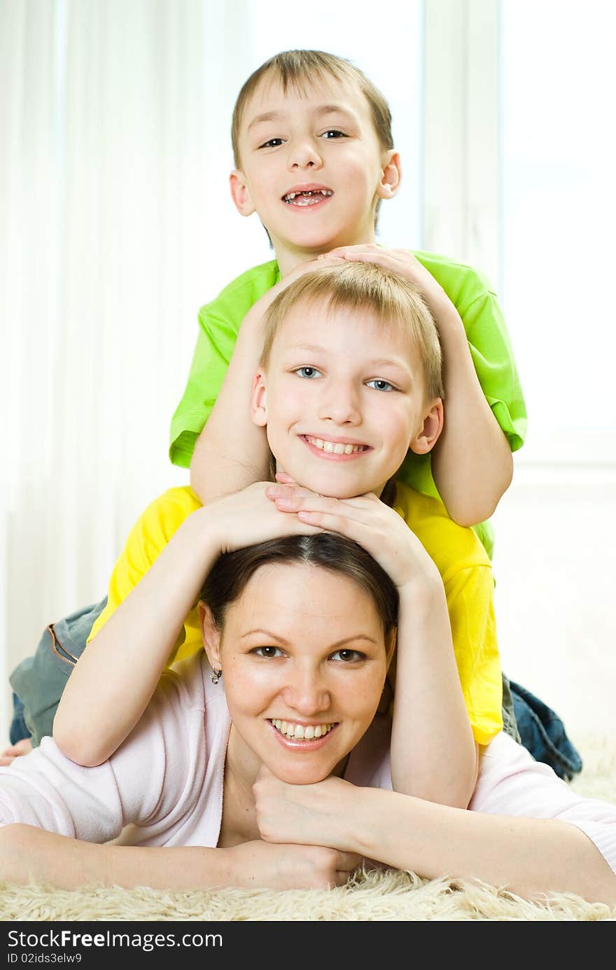 Young mother with her two children lying on the carpet. Young mother with her two children lying on the carpet