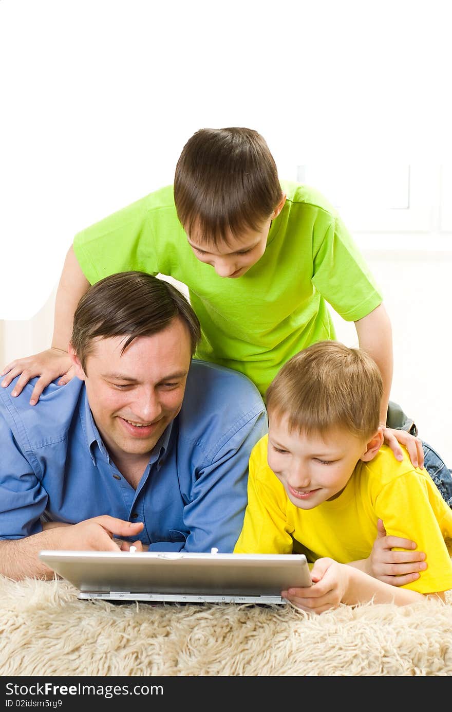 Father with his sons is on the carpet with laptop