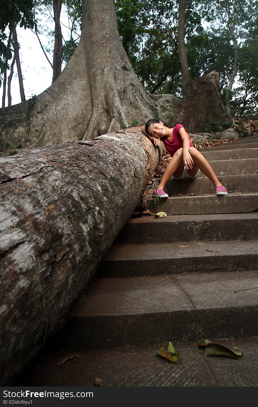 Young happy girl leaning on a dead tree. Young happy girl leaning on a dead tree