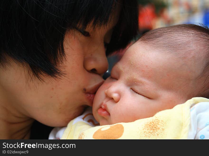 A chinese mother kissing her daughter. loving.