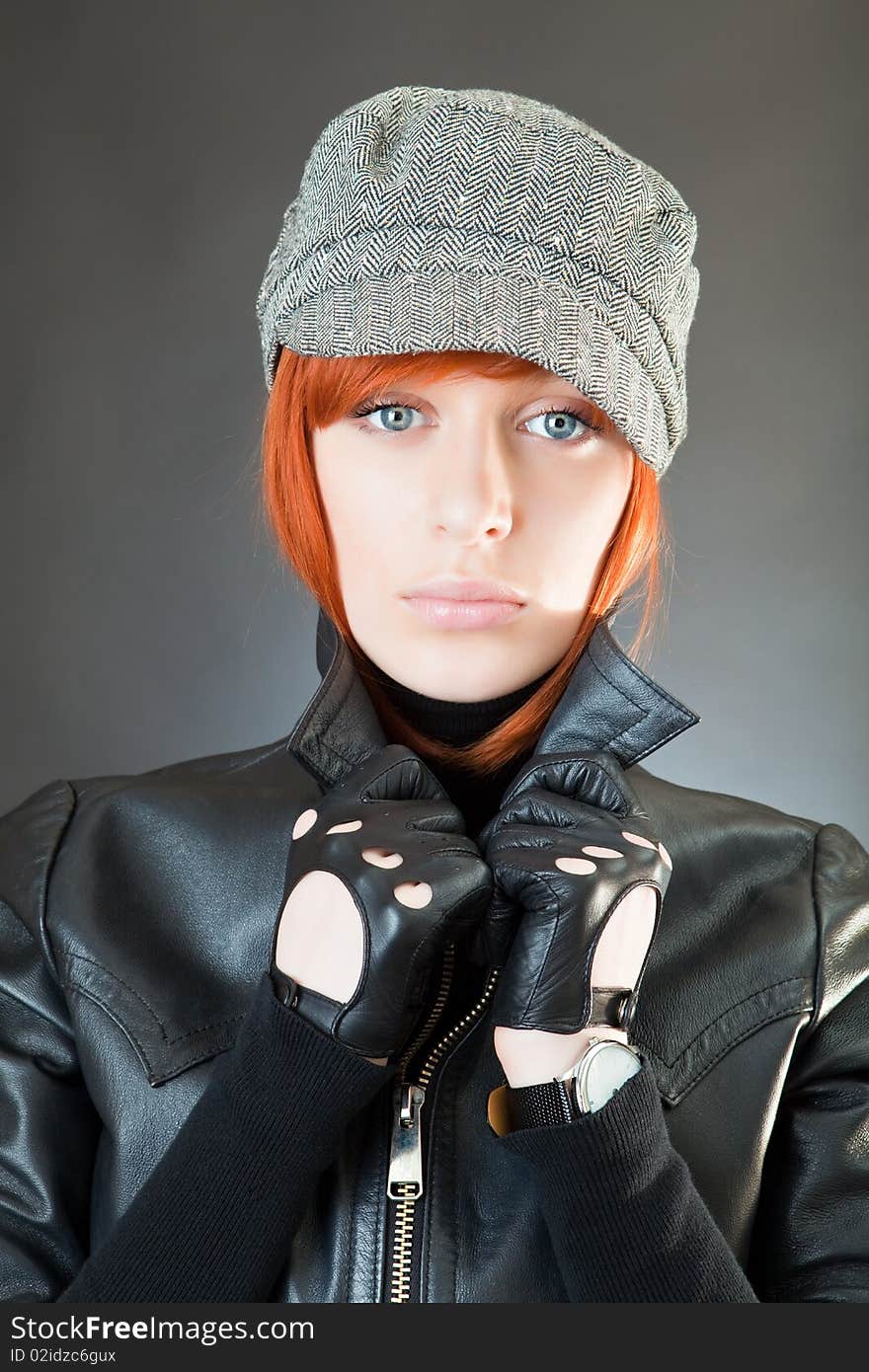 Girl in a suit of the biker against a dark background. Girl in a suit of the biker against a dark background