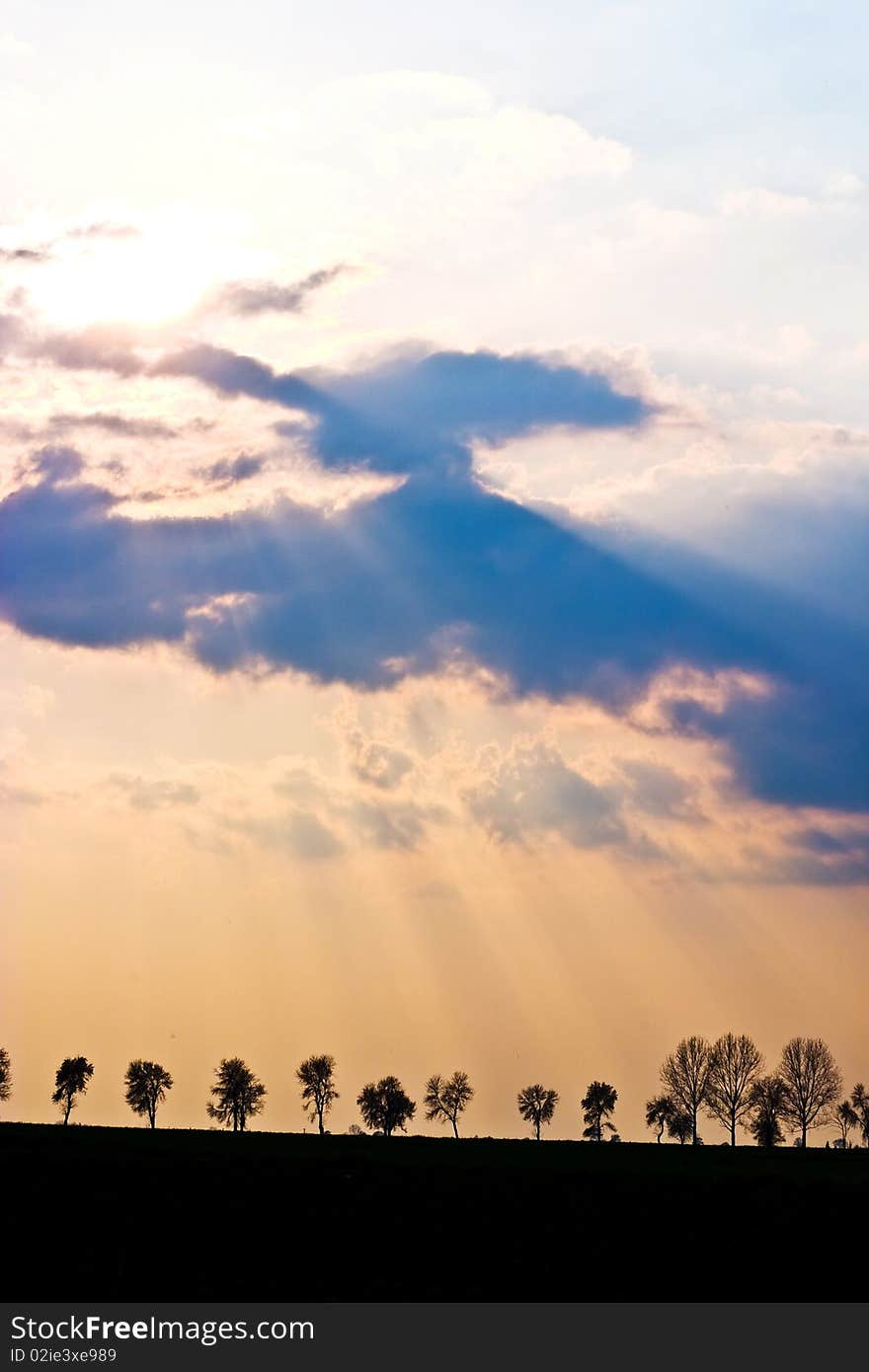 Occurring sun behind the blue clouds on a warm evening