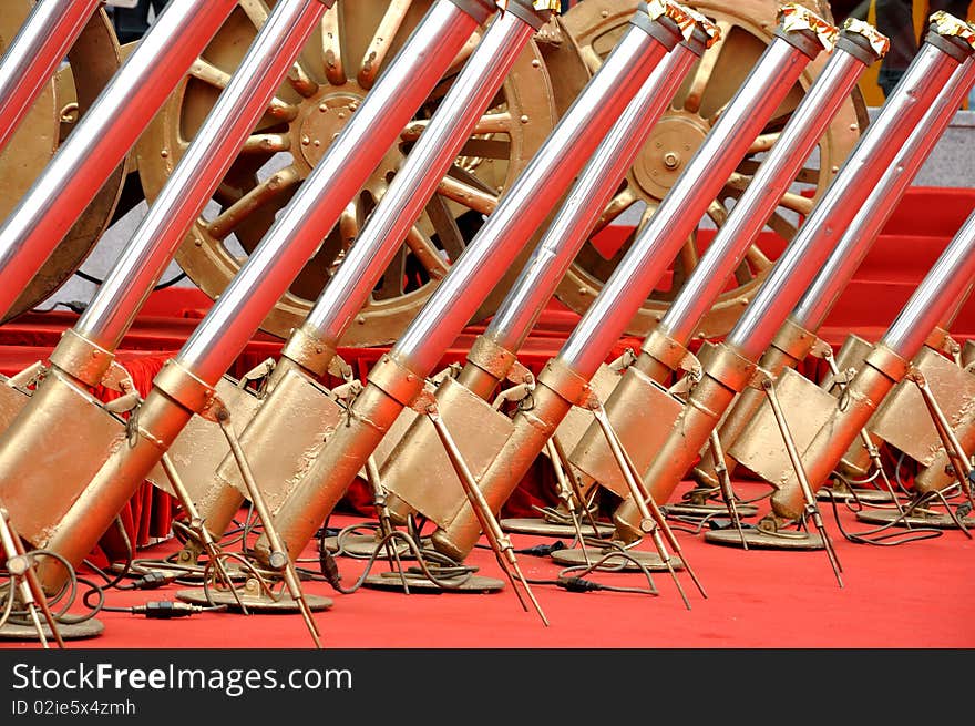 Weel of salute cannon and color strip launcher used in celebration, shown as gold and sliver color and repeated shape, with red background. Weel of salute cannon and color strip launcher used in celebration, shown as gold and sliver color and repeated shape, with red background.