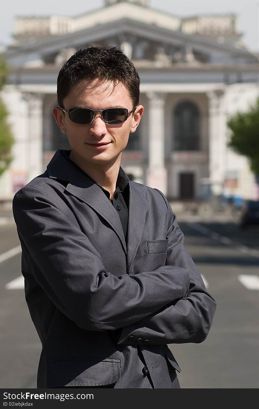 Man standing on the road against big white theater on the background somewhere in Europe. Man standing on the road against big white theater on the background somewhere in Europe