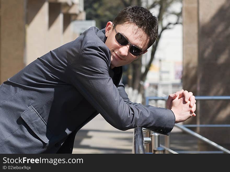 Young adult businessman leans on handrails