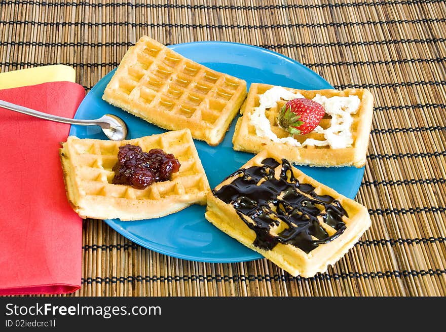 Freshly made waffles with chocolate, jam, honey and strawberries