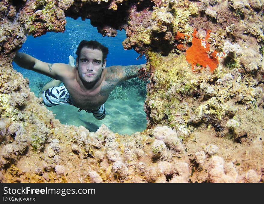 Freediver swimming through coral hole. Freediver swimming through coral hole