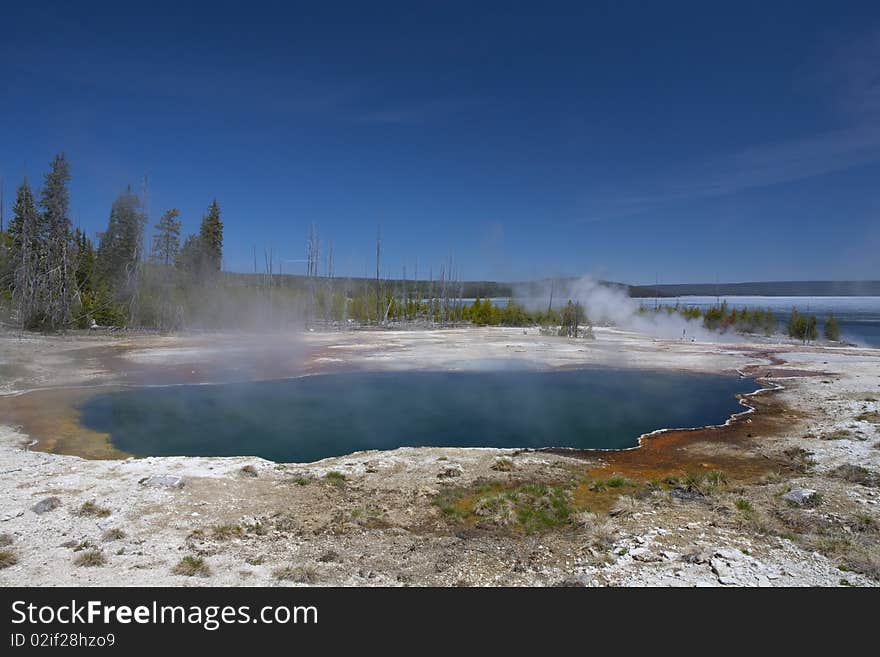 Shore of the lake Yellowstone in the beginning of spring, smoke from the volcanic ground water, geyser