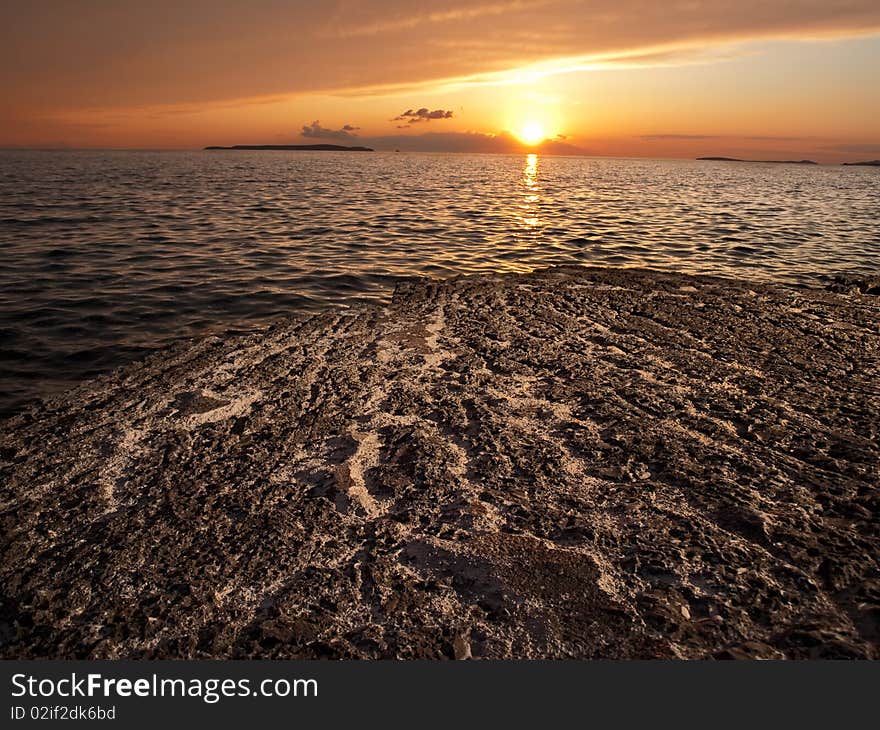 Sunset on the rocky beach with few distant islands on the horizon , Adriatic coast